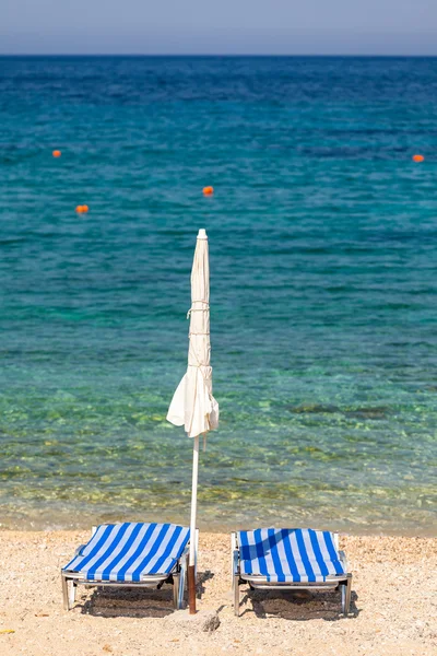 Sun beds and umbrellas on the beach of Mediterranean sea (Crete, — Stock Photo, Image