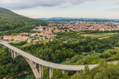 Arka planda Nova Gorica kasabası olan Soca Nehri üzerindeki köprü. Slovenya.