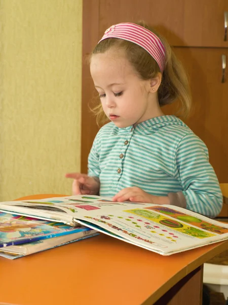 Little girl enthusiastically reviews books on the table — Stock Photo, Image