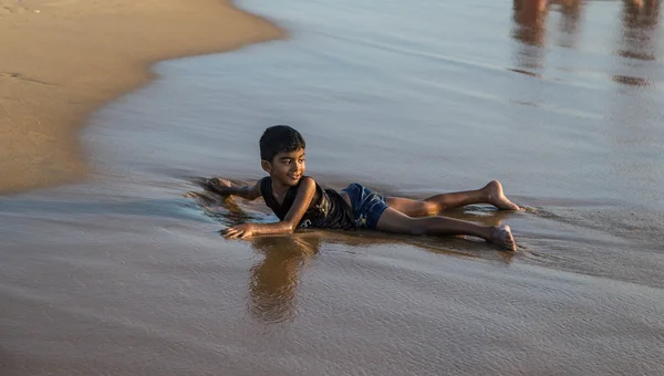 Güvenli bir plajda dalgalarda oynayan bir Güney Asya Sri Lanka çocuğun ortak bir plaj üzerinde samimi resim 