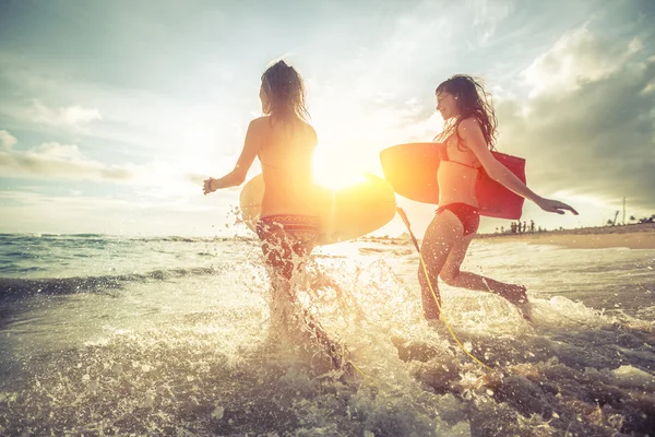 Two young women running into the sea — Stock Photo, Image