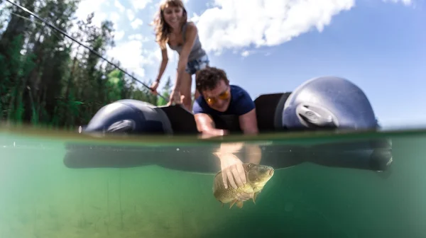 Fisherman in a boat catching a fish — Stock Photo, Image