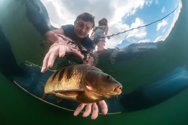 Fisherman in a boat catching a fish — Stock Photo, Image