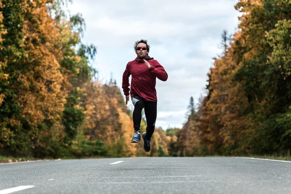 Homem correndo pela estrada na floresta — Fotografia de Stock