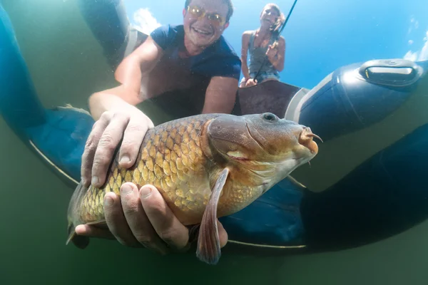 Pêcheur dans un bateau attrapant un poisson — Photo