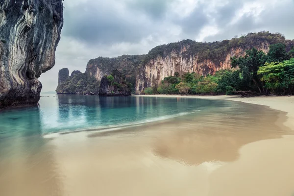 Sandy beach with rocky cliff — Stock Photo, Image