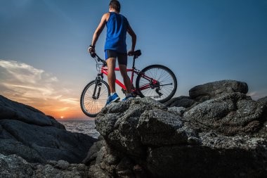Kayanın üzerinde bir bisiklet ile ayakta adam