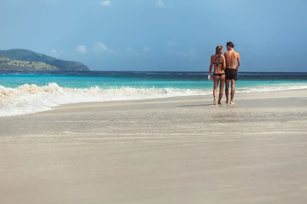 Jeune couple marchant sur une plage de sable fin — Photo