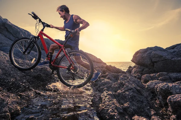 Man carrying a bike on the rock — Stock Photo, Image