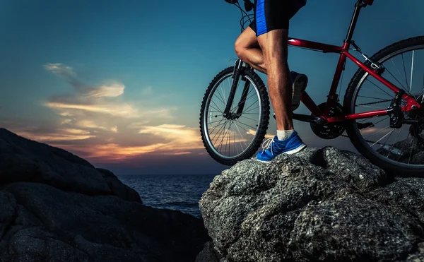 Mężczyzna stojący z rowerem na skale — Zdjęcie stockowe
