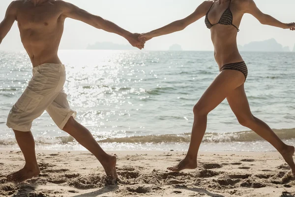 一对年轻夫妇在海滩上奔跑 — 图库照片