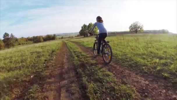 Юная леди катается на велосипеде по проселочной дороге — стоковое видео