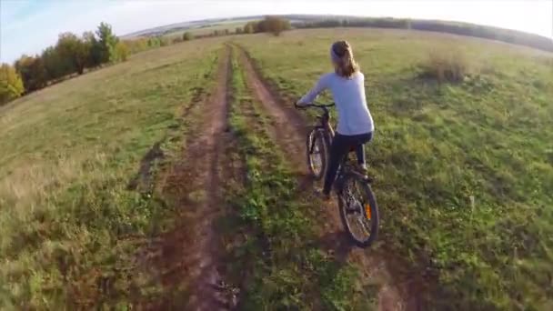 Jonge dame fietsen op een weg van het platteland — Stockvideo