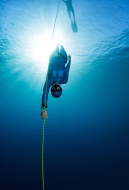Free diver descending along the rope clipart