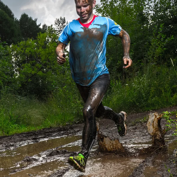 Athlète courir à travers la flaque sale — Photo