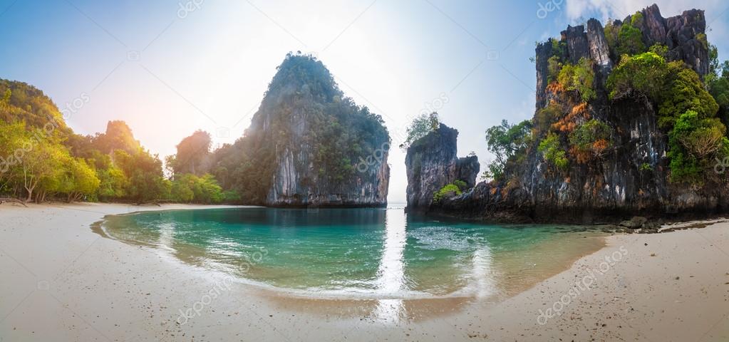 Island with a sandy beach and huge rocky cliff 