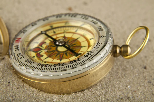 Golden vintage compass on sand background closeup — Stock Photo, Image