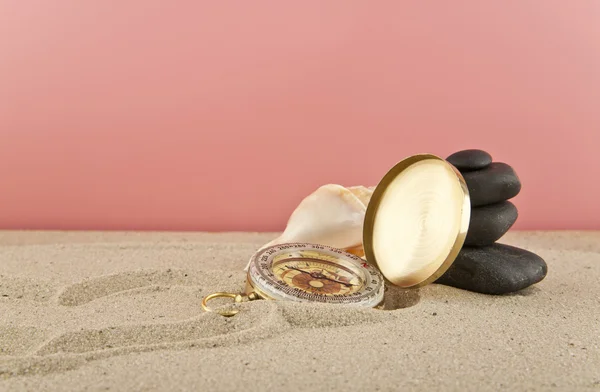 Золотой винтажный компас, раковины и камни на песке — стоковое фото