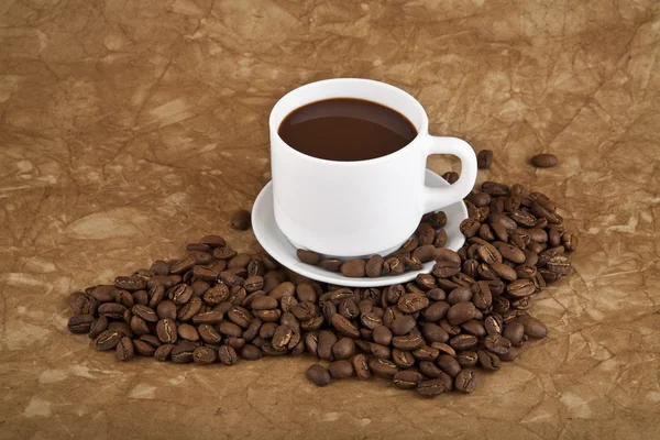 Cup with hot coffee and grains — Stock Photo, Image