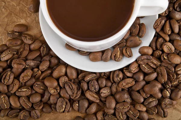 Cup with hot coffee and grains — Stock Photo, Image