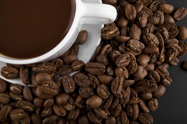 Cup with hot coffee and grains — Stock Photo, Image