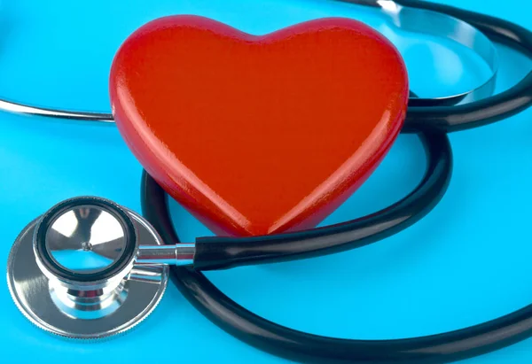 Stethoscope and red heart on a blue background close-up.