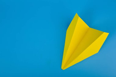 Düz sarı kağıt uçak ve mavi arka plan. Seyahat konsepti Mockup.Yatay. Yukarıdan görünüm.