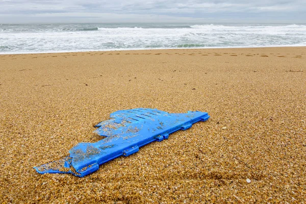 Stuk blauw plastic op strand, vervuilingsconcept — Stockfoto