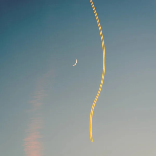 Avion jet, sa traînée et un croissant de lune au coucher du soleil — Photo