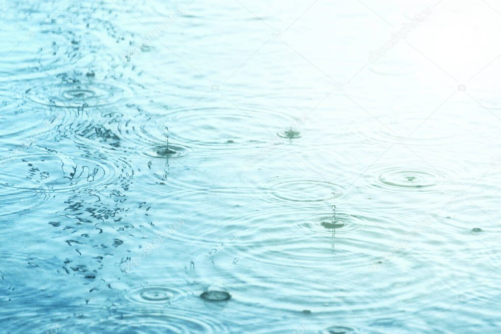 Raindrops creating concentric circles and droplets on water surface