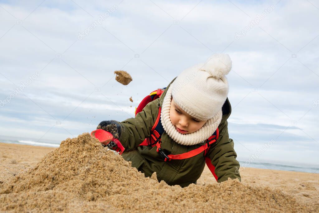 Little boy playing on beach in winter