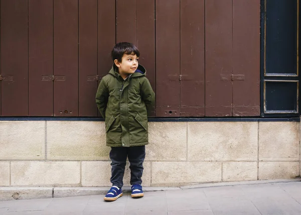 Маленький мальчик в зеленом пальто к стене — стоковое фото