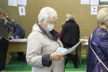 ODESSA, UKRAINE -25.10.2020 - Ukrayna 'da seçimler. COVID-19 Coronavirus salgını sırasında yerel meclis üyelerinin seçim platformu. Oy pusulalarıyla maske ve eldiven takan insanlar