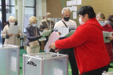 ODESSA, UKRAINE -25.10.2020 - Ukrayna 'da seçimler. COVID-19 Coronavirus salgını sırasında yerel meclis üyelerinin seçim platformu. Oy pusulalarıyla maske ve eldiven takan insanlar