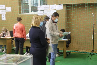 ODESSA, UKRAINE -25.10.2020 - Ukrayna 'da seçimler. COVID-19 Coronavirus salgını sırasında yerel meclis üyelerinin seçim platformu. Oy pusulalarıyla maske ve eldiven takan insanlar