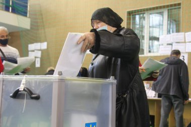 ODESSA, UKRAINE -25.10.2020 - Ukrayna 'da seçimler. COVID-19 Coronavirus salgını sırasında yerel meclis üyelerinin seçim platformu. Oy pusulalarıyla maske ve eldiven takan insanlar