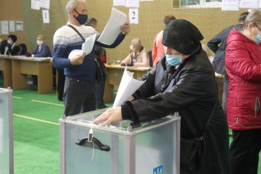 ODESSA, UKRAINE -25.10.2020 - Ukrayna 'da seçimler. COVID-19 Coronavirus salgını sırasında yerel meclis üyelerinin seçim platformu. Oy pusulalarıyla maske ve eldiven takan insanlar