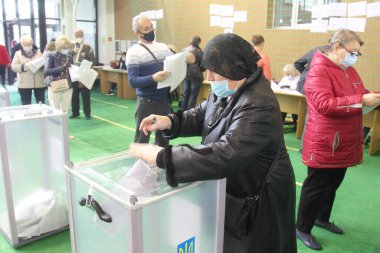ODESSA, UKRAINE -25.10.2020 - Ukrayna 'da seçimler. COVID-19 Coronavirus salgını sırasında yerel meclis üyelerinin seçim platformu. Oy pusulalarıyla maske ve eldiven takan insanlar