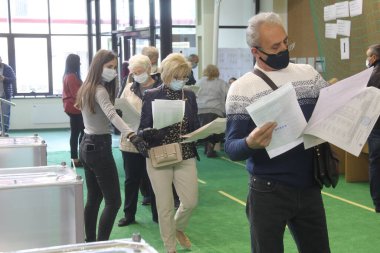 ODESSA, UKRAINE -25.10.2020 - Ukrayna 'da seçimler. COVID-19 Coronavirus salgını sırasında yerel meclis üyelerinin seçim platformu. Oy pusulalarıyla maske ve eldiven takan insanlar