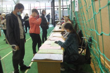 ODESSA, UKRAINE -25.10.2020 - Ukrayna 'da seçimler. COVID-19 Coronavirus salgını sırasında yerel meclis üyelerinin seçim platformu. Oy pusulalarıyla maske ve eldiven takan insanlar