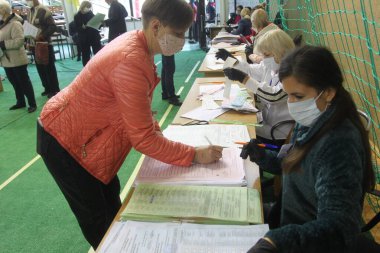 ODESSA, UKRAINE -25.10.2020 - Ukrayna 'da seçimler. COVID-19 Coronavirus salgını sırasında yerel meclis üyelerinin seçim platformu. Oy pusulalarıyla maske ve eldiven takan insanlar