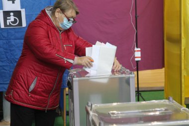 ODESSA, UKRAINE -25.10.2020 - Ukrayna 'da seçimler. COVID-19 Coronavirus salgını sırasında yerel meclis üyelerinin seçim platformu. Oy pusulalarıyla maske ve eldiven takan insanlar
