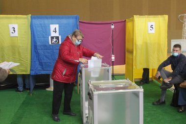 ODESSA, UKRAINE -25.10.2020 - Ukrayna 'da seçimler. COVID-19 Coronavirus salgını sırasında yerel meclis üyelerinin seçim platformu. Oy pusulalarıyla maske ve eldiven takan insanlar