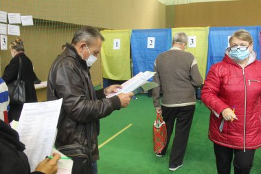 ODESSA, UKRAINE -25.10.2020 - Ukrayna 'da seçimler. COVID-19 Coronavirus salgını sırasında yerel meclis üyelerinin seçim platformu. Oy pusulalarıyla maske ve eldiven takan insanlar