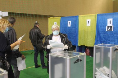 ODESSA, UKRAINE -25.10.2020 - Ukrayna 'da seçimler. COVID-19 Coronavirus salgını sırasında yerel meclis üyelerinin seçim platformu. Oy pusulalarıyla maske ve eldiven takan insanlar