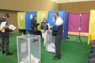 ODESSA, UKRAINE -25.10.2020 - Ukrayna 'da seçimler. COVID-19 Coronavirus salgını sırasında yerel meclis üyelerinin seçim platformu. Oy pusulalarıyla maske ve eldiven takan insanlar