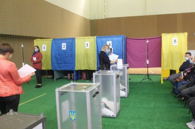 ODESSA, UKRAINE -25.10.2020 - Ukrayna 'da seçimler. COVID-19 Coronavirus salgını sırasında yerel meclis üyelerinin seçim platformu. Oy pusulalarıyla maske ve eldiven takan insanlar