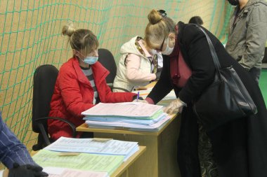 ODESSA, UKRAINE -25.10.2020 - Ukrayna 'da seçimler. COVID-19 Coronavirus salgını sırasında yerel meclis üyelerinin seçim platformu. Oy pusulalarıyla maske ve eldiven takan insanlar