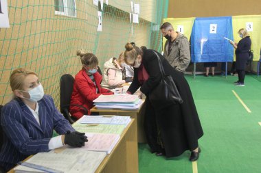 ODESSA, UKRAINE -25.10.2020 - Ukrayna 'da seçimler. COVID-19 Coronavirus salgını sırasında yerel meclis üyelerinin seçim platformu. Oy pusulalarıyla maske ve eldiven takan insanlar