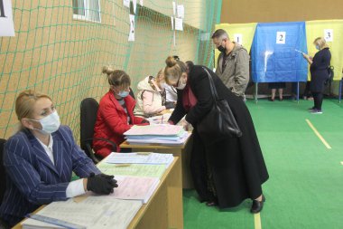 ODESSA, UKRAINE -25.10.2020 - Ukrayna 'da seçimler. COVID-19 Coronavirus salgını sırasında yerel meclis üyelerinin seçim platformu. Oy pusulalarıyla maske ve eldiven takan insanlar